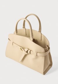 Μπεζ δερμάτινη τσάντα χειρός με δύο στρογγυλεμένες λαβές, λεπτομέρεια μπροστινής ζώνης με χρυσή αγκράφα και δομημένο, λίγο κυρτό σχήμα.