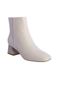 Bota tobillo de cuero blanco con punta afilada y tacón bloque geométrico texturizado. Presenta un diseño sin costuras y un acabado suave.