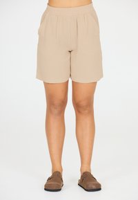 Beige, elastiska shorts i lätt material med sidofickor och ett texturerat, krinklat ytskikt.