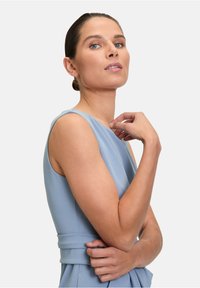 Világoskék, ujjatlan ruha, formás felsőrésszel és derékpánttal. Az sima textúra és a letisztult vonalak kiemelik a minimalista designt.