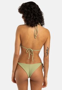 Grön randig bikini med justerbara snören i nacken och på ryggen. Underdelen har en låg midja. Slät textur med minimal detaljering.
