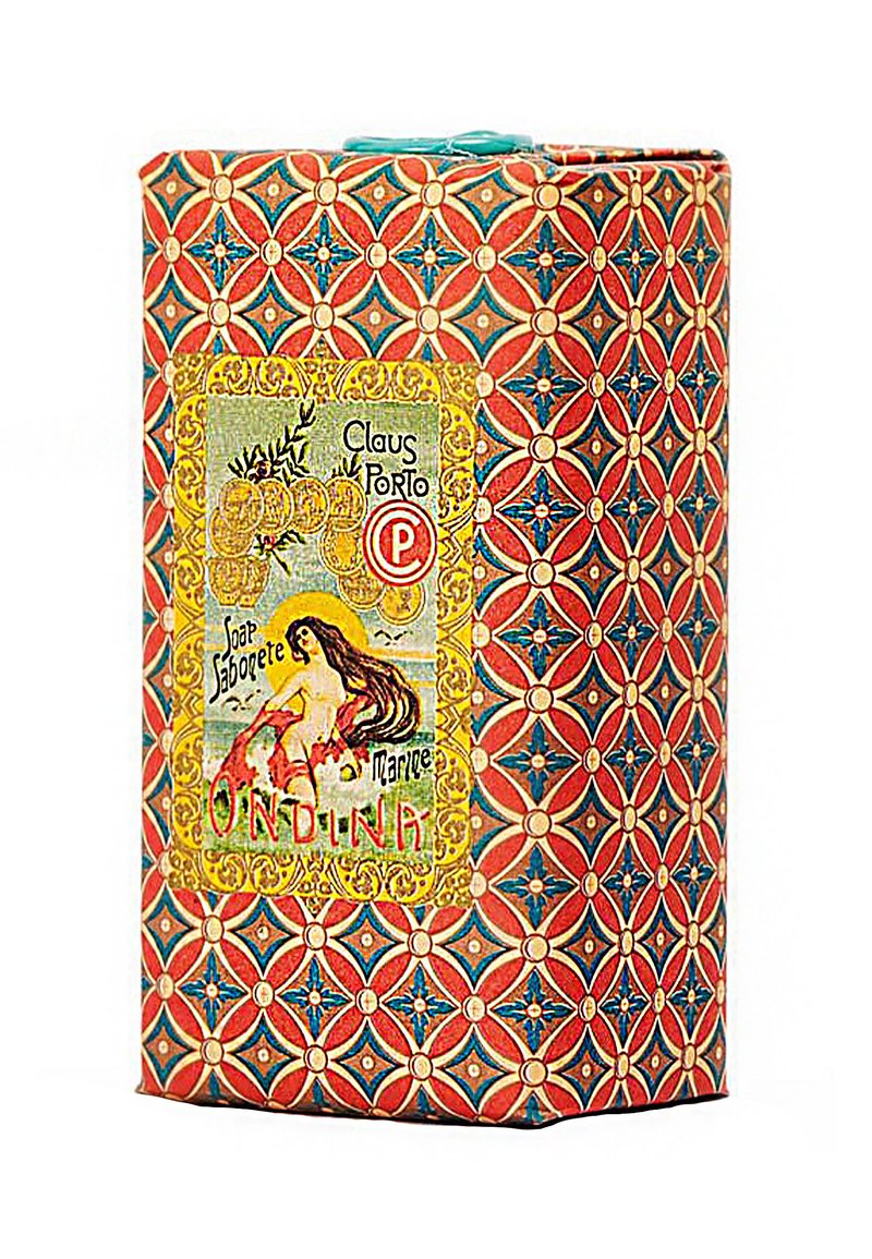 Een gestructureerde zeepdoos met een rood en blauw geometrisch ontwerp, voorzien van een geel en groen etiket met de tekst "Claus Porto Ondina."