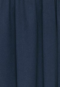 Tissu bleu foncé avec une surface tissée texturée. Le matériau tombe doucement, présentant des variations subtiles de couleur et de profondeur.