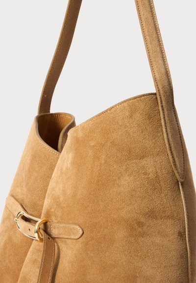 Suède schoudertas in lichtbruin, met een gladde textuur, een geplooid ontwerp, een smalle strap en een gouden gesp accent.