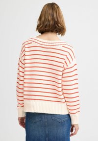 Gestreepte trui in crème met rode strepen, met een losse pasvorm, geribbelde zoom en brede bootnek, gecombineerd met een denim rok.