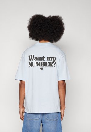 Jasnoniebieska koszulka z krótkim rękawem z wyraźnym czarnym napisem na plecach: "Chcesz mój NUMER?" z małym serduszkiem poniżej.