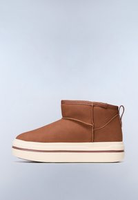 Botas marrones de tobillo con un acabado mate y suave, que cuentan con un forro suave, puntera redondeada y una suela blanca con una sutil raya marrón.