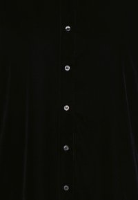 Camicia in velluto nero con davanti a bottoni e bottoni silver, dal tessuto morbido. Senza fantasie, design semplice con una silhouette classica.