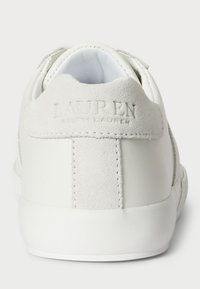 Białe sneakersy z gładkiej skóry i zamszu, z wytłoczonym napisem "LAUREN" na pięcie, okrągłym noskiem i płaską gumową podeszwą.