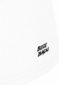 Tela blanca con texto estilizado en negro "BIDI BADU" impreso cerca del borde.