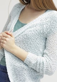Lichtblauwe, gebreide cardigan met een gestructureerde weef. Open voorkant, lange mouwen en geribde manchetten. Draag over een teal top.