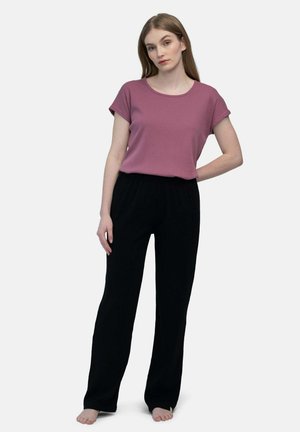 Kurzärmliges, geripptes Top in Lavendel mit lockeren, schwarzen, strukturierten Hosen kombiniert. Einfaches Design, neutrale Farben, entspannte Passform.