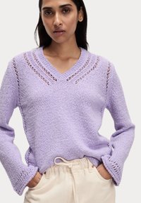 Maglione a maglia lavanda con scollatura a V, caratterizzato da dettagli a punto aperto su spalle e maniche, maniche lunghe e una vestibilità rilassata.