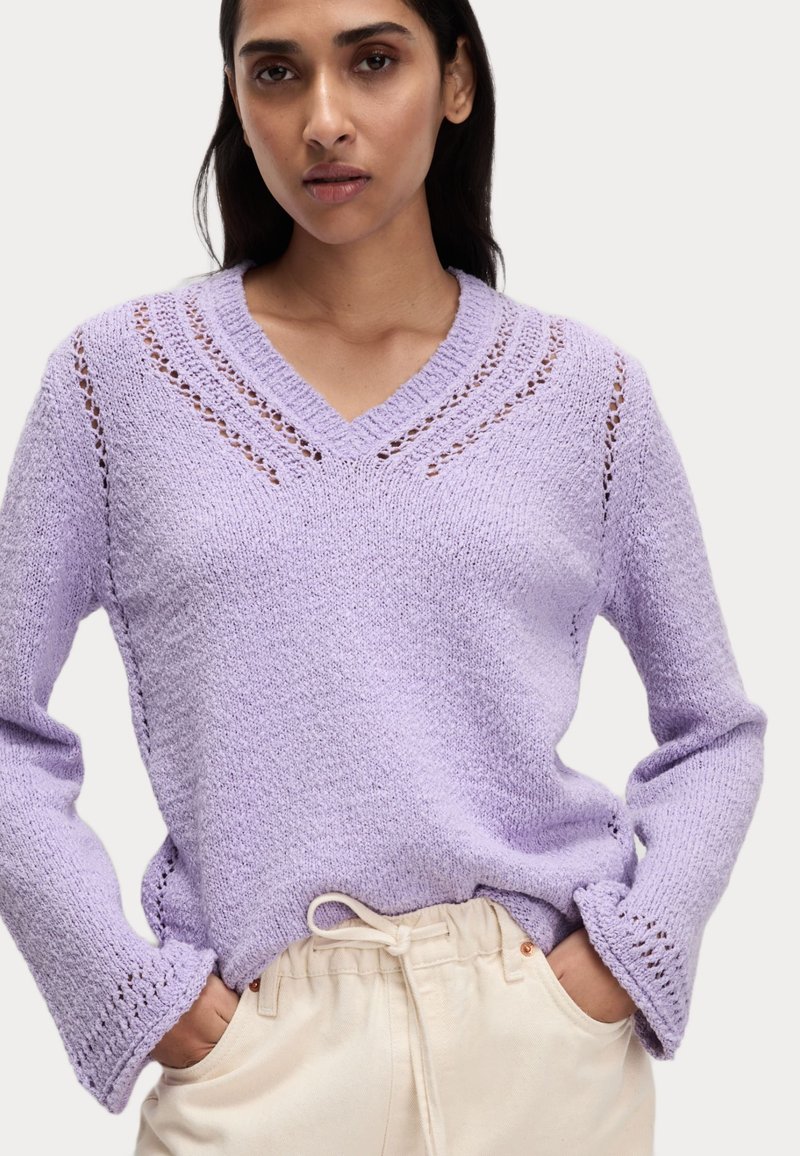 Maglione a maglia lavanda con scollatura a V, caratterizzato da dettagli a punto aperto su spalle e maniche, maniche lunghe e una vestibilità rilassata.