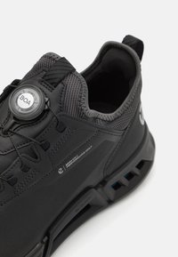 Black golf shoes featuring a textured synthetic upper, BOA closure system, and a sturdy sole with blue accents for traction.