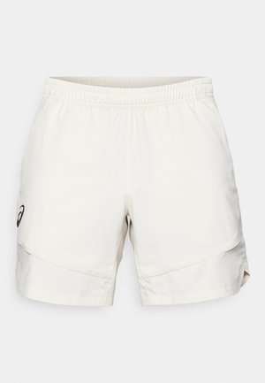 Pantaloni sportivi beige chiaro con vita elasticizzata, tasche laterali e un discreto logo nero sul lato sinistro. Tessuto dalla consistenza liscia.