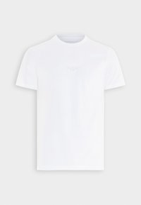 T-shirt bianca a maniche corte con collo a giro e logo "GUESS" ricamato in modo discreto al centro del petto su sfondo semplice.