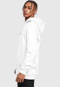 Sudadera blanca hecha de mezcla de algodón, con un bolsillo delantero, capucha con cordones y puños de canalé. Textura suave y corte relajado.