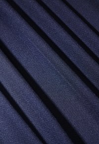 Marinblått tyg med en slät yta, som har snedställda linjer och en subtil lyster, vilket indikerar ett vävt mönster.