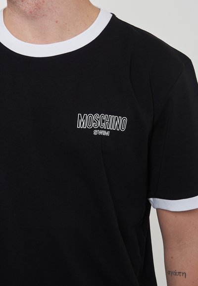 T-shirt in cotone nero con colletto a coste bianco. Presenta un piccolo logo Moschino Swim bianco sul petto. Maniche corte, texture liscia.