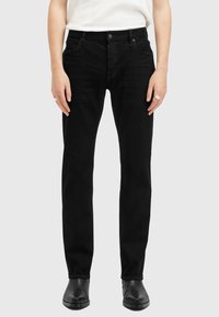 Jeans de mezclilla negra con un corte ajustado, que cuentan con un diseño de cinco bolsillos, lazos para cinturón y una cintura de altura media. Textura suave y costuras mínimas.