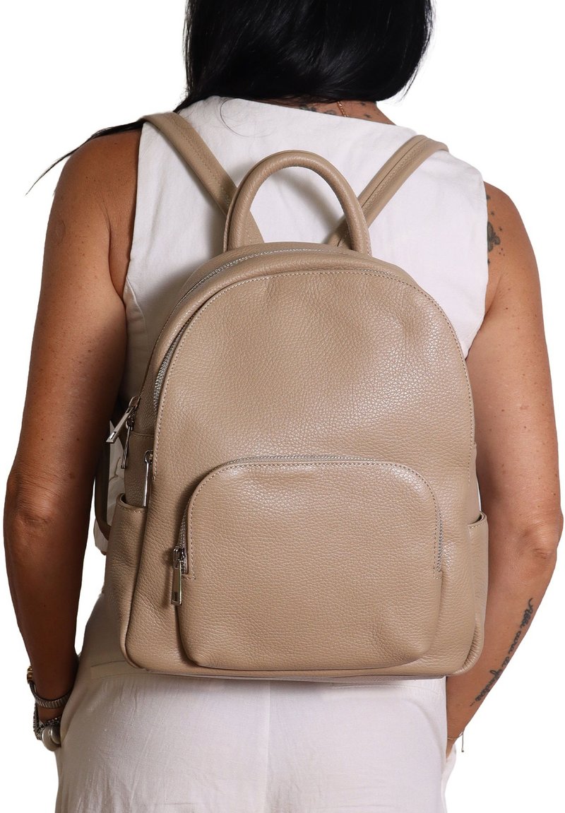 Zaino in pelle beige con forma arrotondata, tasca anteriore con zip e spallacci regolabili. Superficie testurizzata e manico superiore per una facile portabilità.