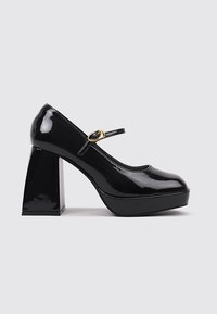 Zapatos de charol negros con tacón cuadrado, punta redonda, correa al tobillo y detalle en tono dorado en la hebilla; acabado brillante y diseño moderno.