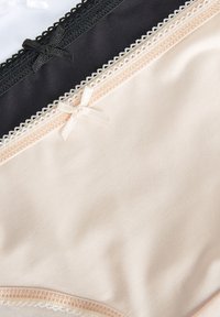 Tri parovi ženskog donjeg rublja u bež, crnoj i bijeloj boji. Svaki par ima čipkastu obrubu, mali detalj u obliku mašne i glatku teksturu.