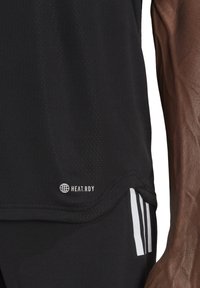 Zwarte sporttop van gestructureerde stof met een "HEAT.RDY" logo, voorzien van contrasterende witte strepen aan de onderrand en zijkant.
