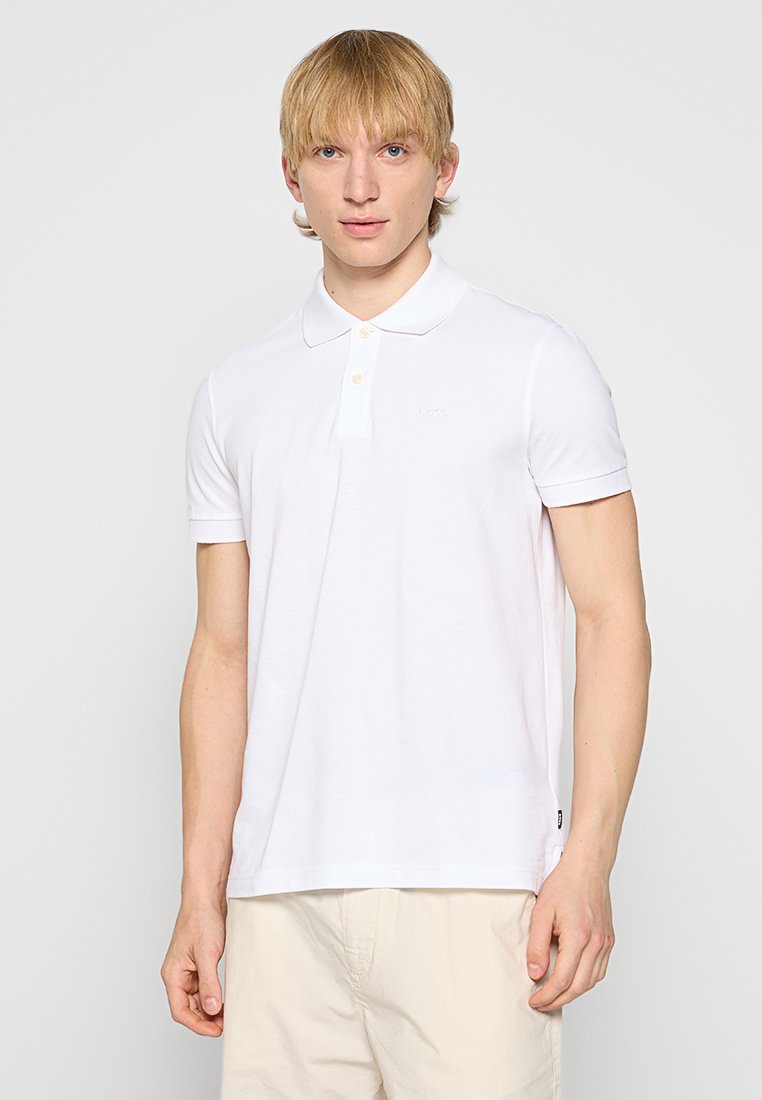 Polo shirt en coton blanc avec une patte de boutonnage à trois boutons et des manches courtes. Présente un logo discret sur la poitrine et un ourlet droit.