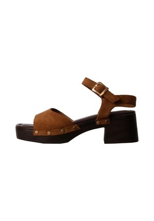 Sandalia de plataforma de ante marrón con pulsera al tobillo, hebilla dorada, puntera abierta, suela de madera y detalles de tachuelas metálicas en el lateral.