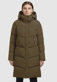 Khakifarbener Puffer-Mantel mit Kapuze, ausgestattet mit einem gesteppten Design, großen Seitentaschen und Knopfdetails entlang der Knopfleiste. Weicher Stoff.