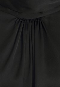 Tissu noir avec des plis froncés sous une ceinture ou un col plié, créant de douces plis verticaux et une texture.