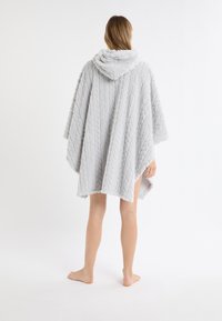 Jasnoszary poncho z kapturem wykonane z teksturowanej pluszowej tkaniny, z wzorem warkocza i luźnym krojem, z wykończonymi krawędziami.