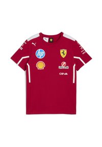 Sarkana Ferrari sacīkšu T-kreklā ar Puma logotipu, Shell, HP, UniCredit, Ceva sponsoriem un dzelteno Ferrari vairogu uz krūtīm un pleciem.