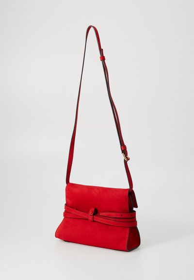 Geantă de umăr din suede roșu, cu bretele ajustabile, având clapetă frontală și un accent legat. Textură netedă și formă rectangulară.