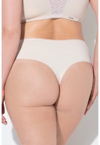 Culotte en coton beige au toucher lisse, avec de délicates bordures festonnées. La taille haute couvre le bas du dos.
