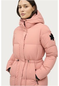 Gevoerde roze jas met een getailleerde taille, een hoge kraag en een geborduurde zwarte sneeuwvlok op de mouw. Rits aan de voorkant en verstelbare trekkoorden.