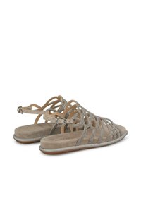 Beżowe zamszowe sandały z błyszczącymi srebrnymi akcentami, z wiązaniami i regulowanym zapięciem. Płaskie podeszwy o teksturowanej powierzchni.