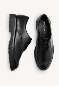 Paire de chaussures noires en cuir à lacets avec semelles épaisses et robustes, l’une vue de côté et l’autre vue de dessus, taille 37.
