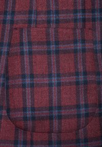 Czerwono-niebieska tkanina w kratę z dużą kieszenią o zaokrąglonych krawędziach, pokazująca teksturowany splot przez całą powierzchnię.