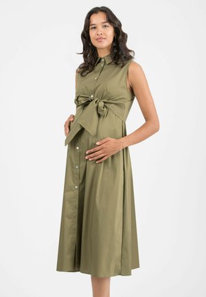 Olive green, sleeveless dress with a button-up front and a bow tie at the waist. Flowing skirt, smooth texture, and knee-length design.