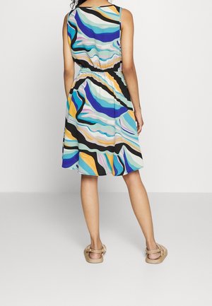 Robe sans manches avec un motif de vagues multicolores en bleu, jaune et noir. Taille élastique, longueur genou, associée à des sandales plates.