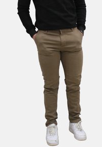 Khaki slim-fit broek van een katoenmengsel, met een zachte textuur en vijf zakken, gecombineerd met witte sneakers.