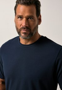 Námorně modré bavlněné tričko s kulatým výstřihem a krátkými rukávy, hladká textura a jednoduchý design bez vzorů nebo akcentů.