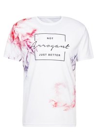 Camiseta blanca con estampado de humo rojo y púrpura en las mangas, que presenta un diseño rectangular negro con el texto "NO Arrogante, SOLO MEJOR."