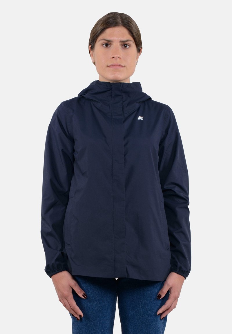 Giacca leggera blu navy con cappuccio, polsini elasticizzati e zip frontale completa. Presenta un piccolo logo sulla parte superiore sinistra del petto. Texture liscia.