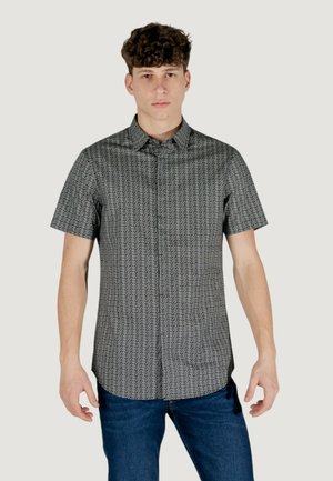 Chemise à manches courtes avec col, en motif géométrique noir et blanc, fabriquée en tissu léger, avec un devant à boutons et un ourlet droit.