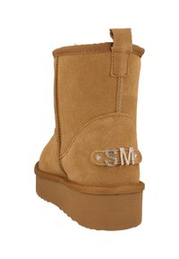 Stivaletto alla caviglia in camoscio color cognac con una linguetta posteriore, suola testurizzata e decorazioni argento con le iniziali "SM".