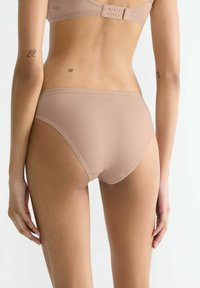 Beige Hochtaillenslips aus glattem Stoff, nahtlosen Kanten und einem dezenten Logo. Verfügt über einen bequemen Gummibund und minimalen Rückendeckung.